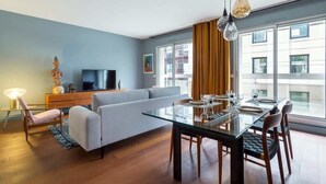 A modern living room with a glass dining table, sofa, and television. - Stella - Furnished apartment - Downtown Lyon (Lyon)