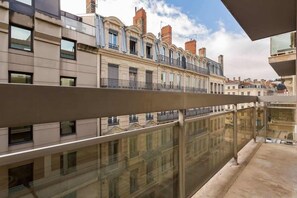 A modern building with a glass balcony overlooking a row of traditional buildings.