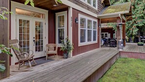 A wooden deck with two rocking chairs and a potted plant, leading to a house with a number 8920 on the door. - 3 Bedroom Sleeps 6, Hot Tub, Exec home, Workspace incl. desk,  (Swansea Point)