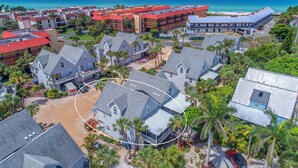 Eine Vogelperspektive eines Küstenresorts mit mehreren Gebäuden, darunter ein großes Hotel mit rotem Dach und ein kleineres Gebäude mit blauem Dach.