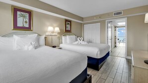 A hotel room with two beds, a desk, and a view of the balcony. - Camelot By the Sea 🏖️ Oceanfront 🏖️ (Myrtle Beach)