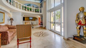 A spacious lobby with a high ceiling, a grand staircase, and a statue. - Camelot By the Sea 🏖️ Oceanfront 🏖️ (Myrtle Beach)
