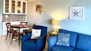 A dining area with a wooden ceiling fan, a dining table with chairs, and a kitchen with cabinets.