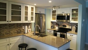 A modern kitchen with white cabinets, stainless steel appliances, and a granite countertop.
