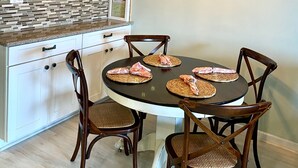A kitchen with white cabinets, a wooden ceiling, and a dining area with a round table and four chairs.