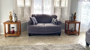 Un salón acogedor con un sofá gris, dos mesitas de madera y una alfombra estampada.