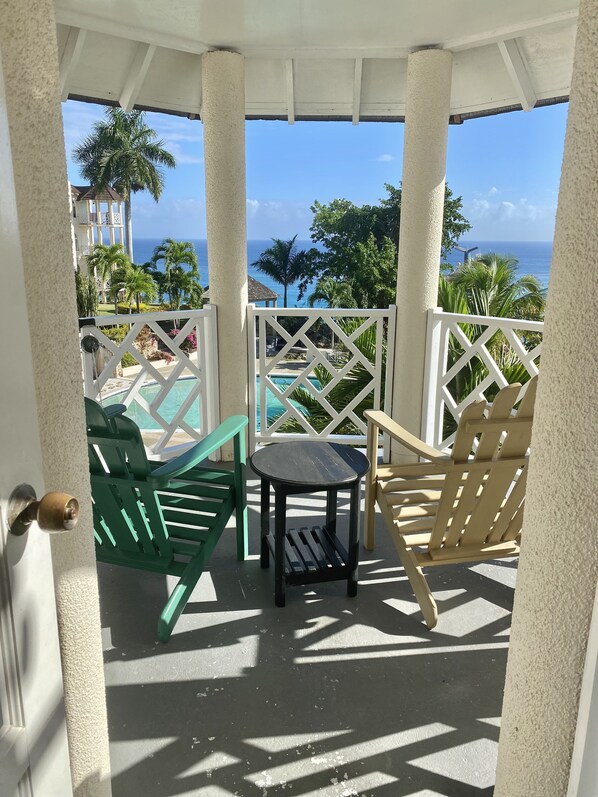 A balcony with a view of the ocean, featuring a small table and two chairs.