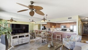A modern living room with a TV, wooden furniture, and ceiling fans.