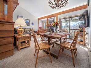 Enjoy meals in this well-appointed dining area with a rustic table for four, a large window offering a view of the outdoors, and a comfortable seating area with a sofa and armchairs.