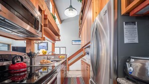 Une cuisine moderne dotée d’appareils électroménagers en acier inoxydable, de meubles en bois et d’un tapis à motifs.