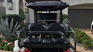 Um carrinho de golfe estacionado em um pátio de pedra, com uma casa ao fundo.