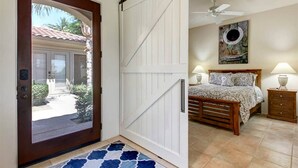 Quarto com uma cama, mesas de cabeceira, ventilador de teto e vista para o exterior.