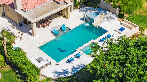 Vista aérea de um quintal com piscina, espreguiçadeiras e banheira de hidromassagem.