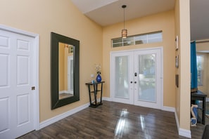 A hallway with a wooden floor, a large mirror, and a door with frosted glass panels. - Beautiful Pool Home Close To Many Beaches (Venice)