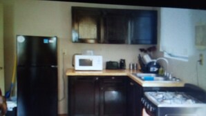 A kitchen with a refrigerator, microwave, stove, and sink.