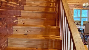 A wooden staircase with a wooden railing, leading to a room with a window and a table. - Trumpeter Lodge located on the banks of Little Red River, Heber Springs,Arkansas (Heber Springs)