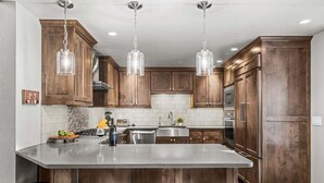 Une cuisine moderne avec des meubles en bois, des appareils en acier inoxydable et un îlot central doté de tabourets de bar.