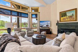 A spacious living room with a large window, a fireplace, and a television.