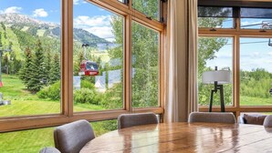 A conference room with large windows, a wooden table, and chairs. - RMR: Cody House B Condo in Teton Village (Teton Village)