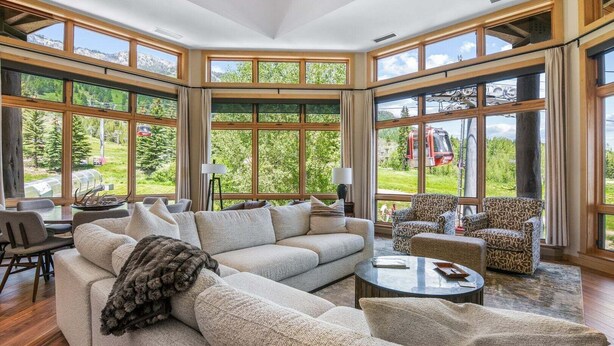 A spacious living room with a large sectional sofa, two armchairs, a coffee table, and a view of a mountainous landscape through large windows. - RMR: Cody House B Condo in Teton Village (Teton Village)