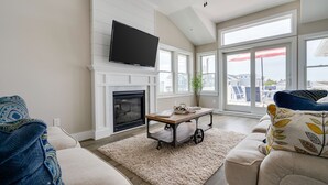 Una sala de estar con chimenea, televisor montado arriba, un sofá y una mesa de centro.