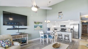 Une cuisine moderne avec des meubles blancs, un réfrigérateur en acier inoxydable et un coin repas avec des chaises blanches.