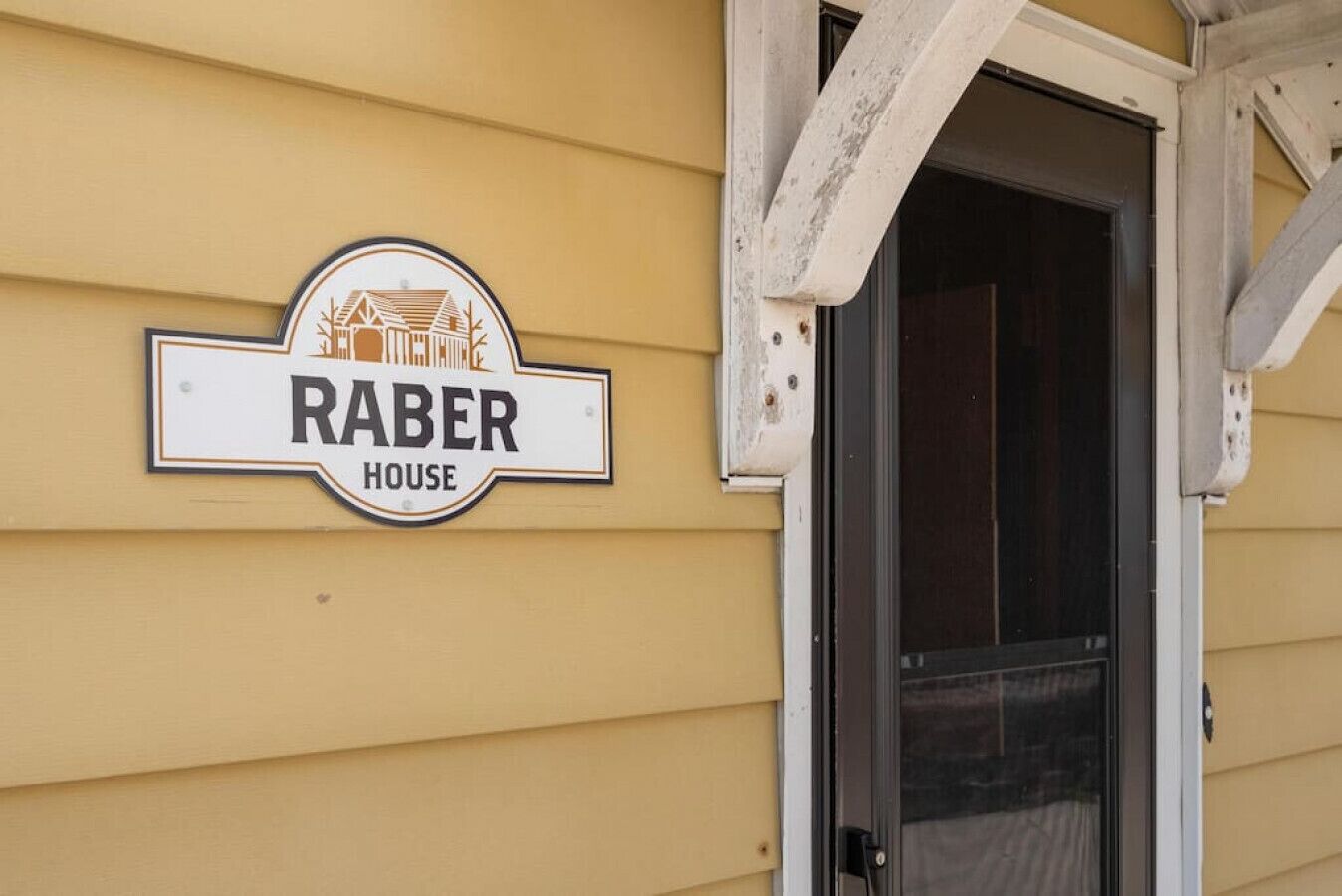 Un bâtiment sur lequel on peut lire l’inscription « RABER HOUSE » et dont la porte est dotée d’un panneau de verre.