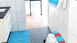 A modern bathroom with white tiles, a blue towel rack, and a visible sink area.