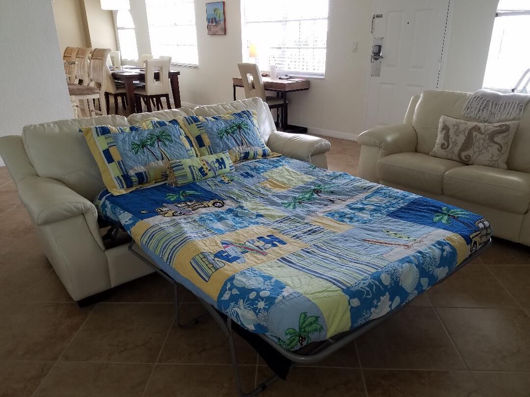 Un dormitorio con una cama, dos sofás, una mesa de comedor y sillas.