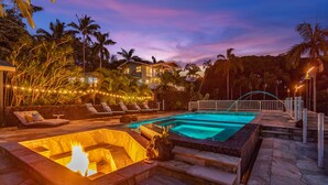 Piscina con chimenea, sillas de descanso y terraza de piedra.