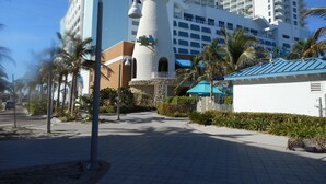 A hotel with a prominent tower, palm trees, and a paved walkway.