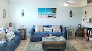 A living room with a blue sofa, a coffee table, and a ceiling fan.