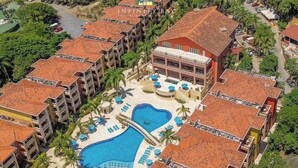 A resort with multiple buildings, a central swimming pool, and surrounding palm trees. - “Our Paradise Found” Condo 1405 at Infinity Bay (West Bay Beach, Roatan)