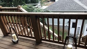 A wooden deck with two glass candle holders, one with a candle and the other empty.
