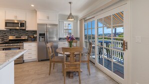 A modern kitchen with stainless steel appliances, a dining area with wooden chairs, and a large sliding glass door leading to a balcony. - Great Lantern District Location!.. Central AC!...Ocean View<br> (Dana Point)