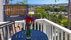 A balcony with a table, chairs, and a vase of flowers. - Great Lantern District Location!.. Central AC!...Ocean View<br> (Dana Point)