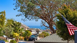 A residential street with houses, a parked SUV, and a large tree with an American flag. - Great Lantern District Location!.. Central AC!...Ocean View<br> (Dana Point)