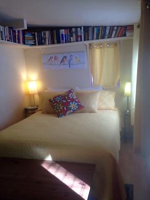 Cozy retreat with a neatly made bed, bedside table, and reading nook.