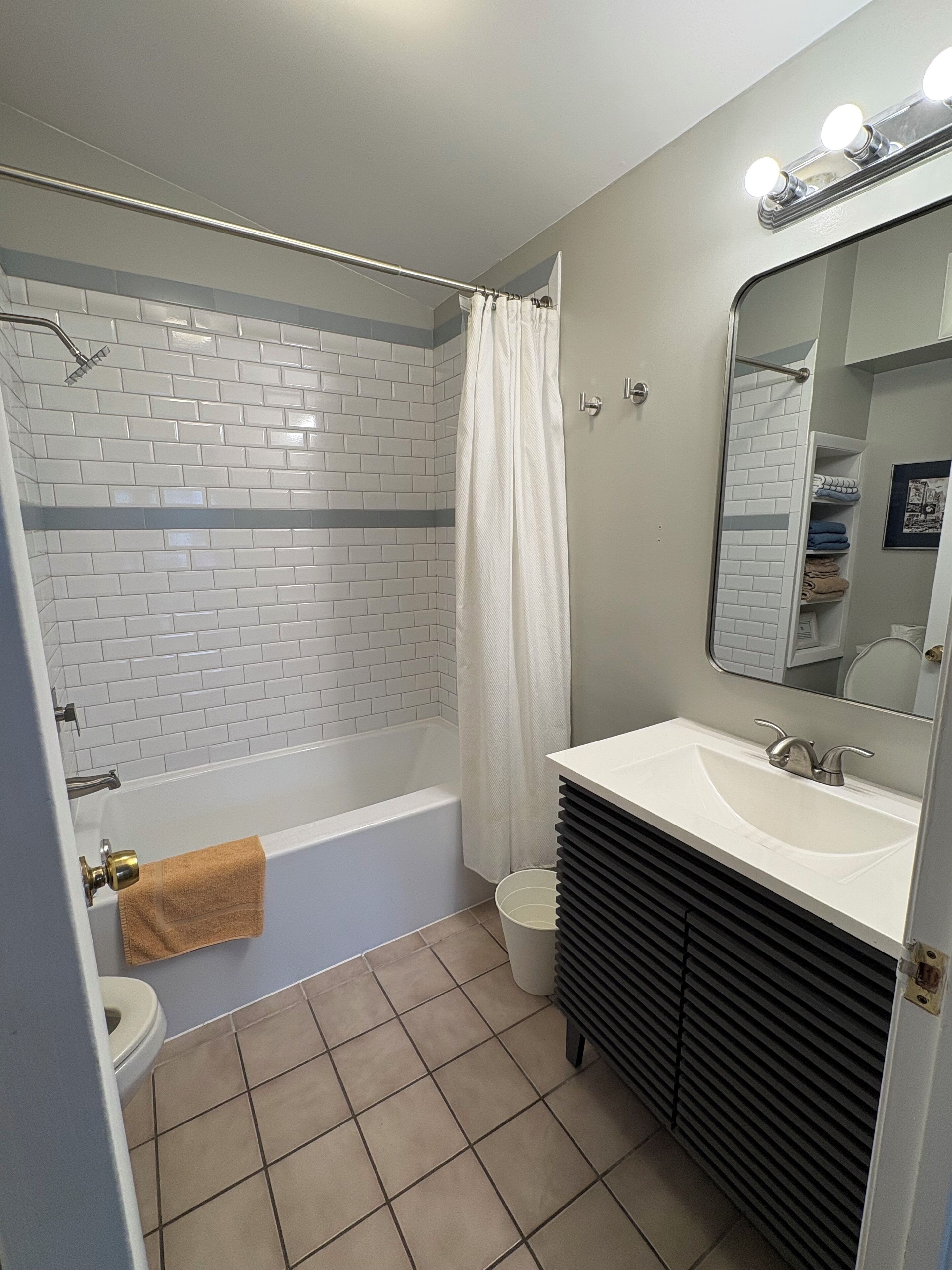 A bathroom with a white bathtub, a sink, a toilet, and a mirror.