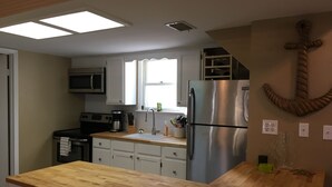 Una cocina moderna con encimera de madera, electrodomésticos de acero inoxidable y un ventanal con vistas.