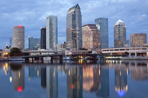 Un horizonte urbano con modernos rascacielos reflejados en aguas tranquilas.