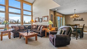 A spacious living room with a large window, a fireplace, and a dining area. - RMR: Greyling 4513 Condo in The Aspens/Wilson,WY (Wilson)