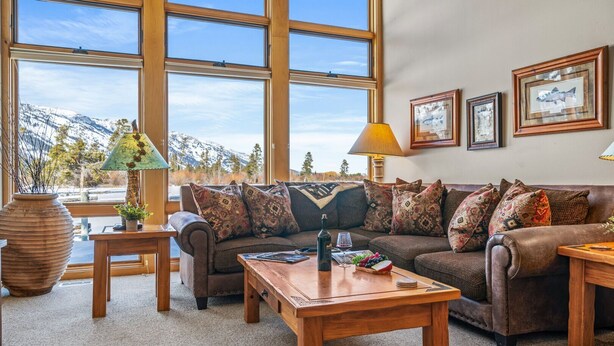 A cozy living room with a large window, a sofa, a coffee table, and a lamp. - RMR: Greyling 4513 Condo in The Aspens/Wilson,WY (Wilson)