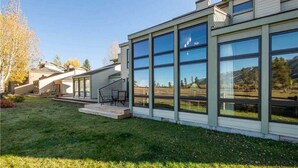 A modern house with large windows, a covered patio, and a view of the surrounding landscape. - RMR: Greyling 4513 Condo in The Aspens/Wilson,WY (Wilson)