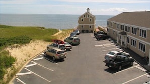 Un estacionamiento con varios autos, un edificio de techo plano y vista al mar.