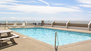 Una piscina con sillones de descanso y vista al océano.