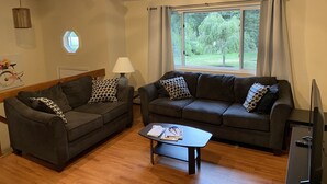 A living room with two dark grey sofas, a small coffee table, and a ceiling fan.