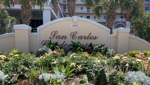 A hotel entrance with a sign reading 'San Carlos Gardens' and a number '365' above it.