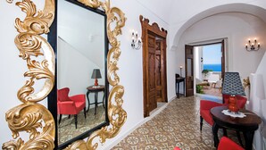 A hallway with a large ornate mirror, red chairs, a patterned floor, and a view of the sea through an open door. - The Most Panoramic Villa In The Center Of Positano (Positano)