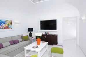 A modern living room with a sofa, coffee table, and a flat-screen TV mounted on the wall.